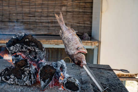 Malaga style of preparation of fresh fish, catch of the day, on skewers and open flame on fireplace with olive trees wood on the beach, Andalusia, Spainの写真素材