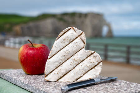 French heartshaped neufchatel cow cheese served outdoor with apple and view on alebaster cliffs Porte d'Aval in Etretat, Normandy, Franceの写真素材
