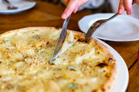 Eating of fresh baked pizza dish in italian pizzeria restaurant, close up