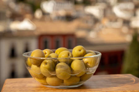 Glass bowl with green andalusian olives served on outdoor terrace with view on old part and white houses of Granada, Andalusia, Spainの写真素材