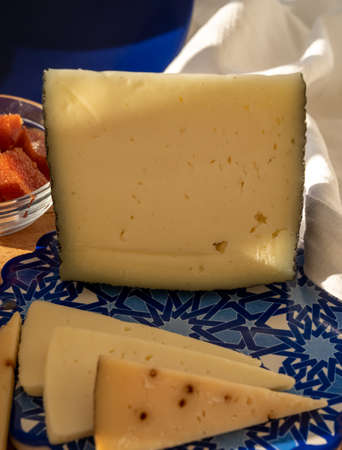 Spanish hard manchego, cow, sheep and goat cheeses served outdoor with membrillo jam in sunlights on...