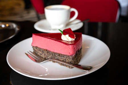 Piece of famous Poppy seed cake with raspberry mousse of Austrian origin served with whipped cream...