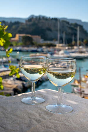 Two glasses of white wine from Cassis wine making region served on outdoor terrace with view on old...