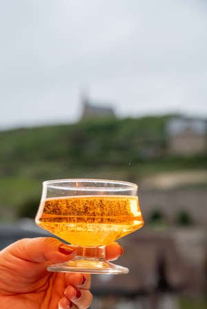 Hand holding one glass of apple cider drink and Etretat village on background, Normandy, Franceの写真素材
