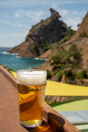 Glass of fresh cold lager beer served outdoor in snack bar with view on Calanque de Figuerolles in...