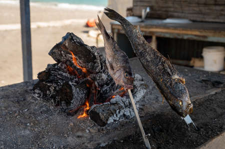 Malaga style of preparation of fresh fish, catch of the day, on skewers and open flame on fireplace...