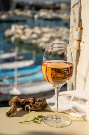Cold rose Provencal wine in glass served in sunlights on outdoor terrace with view on old...