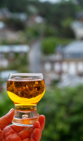 Hand holding one glass of apple cider drink and houses of Etretat village on background, Normandy, Franceの写真素材