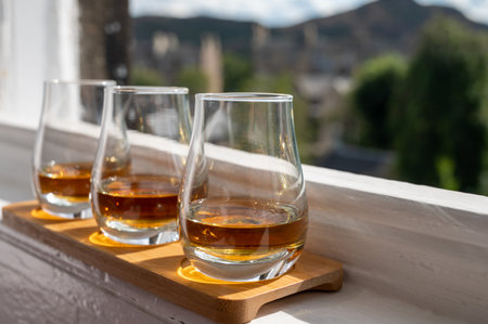 Flight of single malt scotch whiskey served on old window sill in Scottish house with view on old part of Edinburgh city, Scotland, UK, dram of whiskeyの写真素材