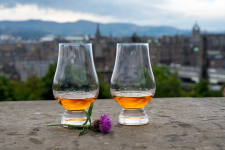 Two glasses of single malt scotch whiskey and view from Calton hill to park and old parts of...