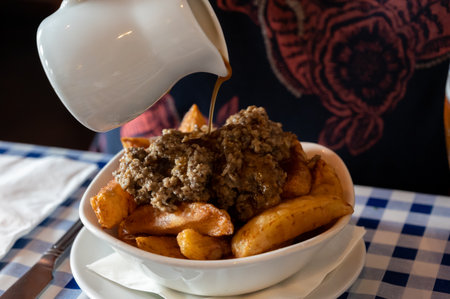 Scottish traditional snack food, hand cut potato chips topped with haggis and gravy served in old...