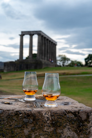 Tasting of single malt scotch whiskey in glasses with panoramic view from Calton hill to new and old parts of Edinburgh city in rainy summer day, Scotland, UKの写真素材