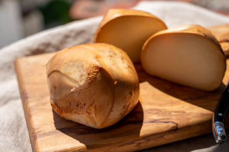 Italian yellow smoked cheese scamorza served on olive tree wooden plank close upの写真素材