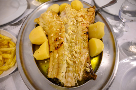 Grilled fillet of white codfish bacalhau served with potatos in fish restaurant in Portugal