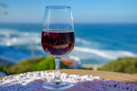 Tasting of tawny porto wine and view on sandy beach and blue Atlantic ocean near Sintra in Lisbon...