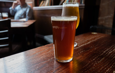 Pint glasses of cold fresh british ale and lager beer served in old vintage English pubの写真素材