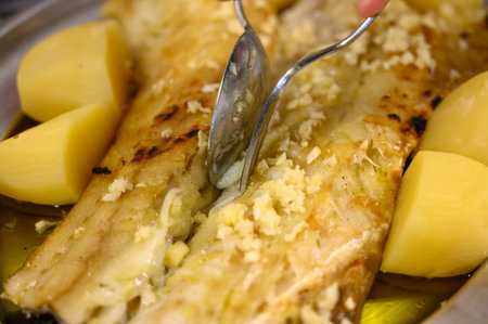 Grilled fillet of white codfish bacalhau served with potatos in fish restaurant in Portugalの写真素材