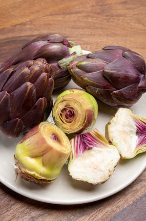 Heads of raw fresh purple romanesco artichoke vegetable heads and pilled hearts ready to cookの写真素材