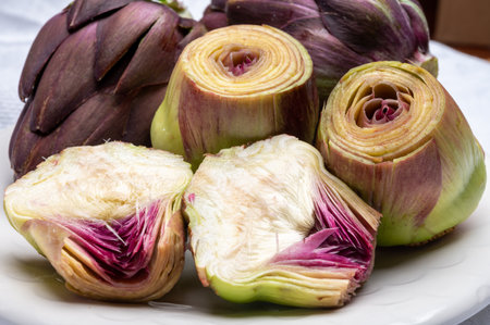 Heads of raw fresh purple romanesco artichoke vegetable heads and pilled hearts ready to cookの写真素材