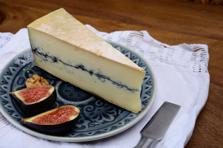French semi-soft cow milk cheese morbier from Franche-Comte region with thin black layer and strong...