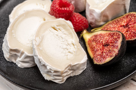 French organic matured white goat cheese with white mold close up served with fresh raspberries and figsの写真素材