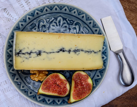 French semi-soft cow milk cheese morbier from Franche-Comte region with thin black layer and strong...