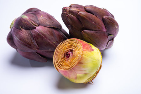 Heads of raw fresh purple romanesco artichoke vegetable heads and pilled hearts ready to cook solated on white backgroundの写真素材