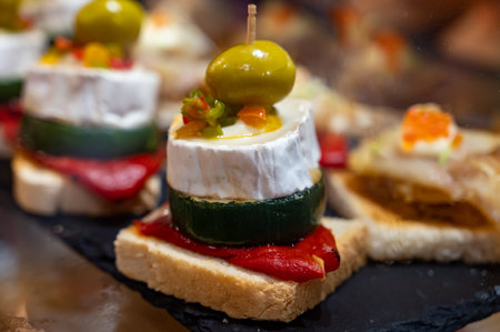 Typical snack of Basque Country, pinchos or pinxtos skewers with small pieces of bread, sea food,...