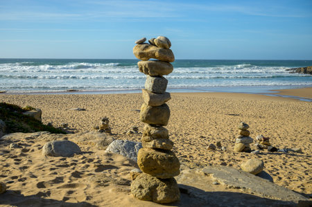 Pyramid from stack balanced stones on sandy beach in sunset, Atlantic ocean, Portugal