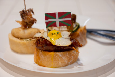 White board with typical snack and flag of Basque Country, pinchos or pinxtos skewers with small...