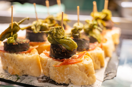 Typical snack of Basque Country, pinchos or pinxtos skewers with small pieces of bread, sea food, eggs, cheese, jamon served in bar in San-Sebastian or Bilbao, Spain, close upの写真素材