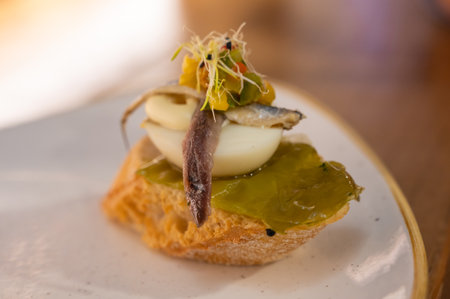 Board with typical snack of Basque Country, pinchos or pinxtos skewers with small pieces of bread, sea food, eggs, cheese served in bar in San-Sebastian or Bilbao, Spain, close upの写真素材