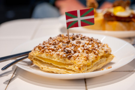 Basque Country food, sweet dessert, puff pastry cake with vanilla cream and hazelnut and flag of Basque Country close up, Spainの写真素材