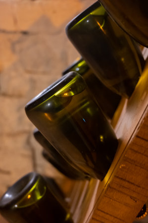 Walking in deep long undergrounds caves with dusty bottles on racks, making champagne sparkling wine...