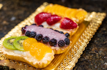 Delicious fresh baked colorful decorated cakes, tarts with cream and fruits on display in banquet...
