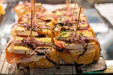 Typical snack of Basque Country, pinchos or pinxtos skewers with small pieces of bread, sea food, eggs, cheese, jamon served in bar in San-Sebastian or Bilbao, Spain, close upの素材 [FY310197412570]