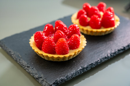 Artisanal baked small tart with cream and fresh ripe red raspberry, tasty french dessertの写真素材