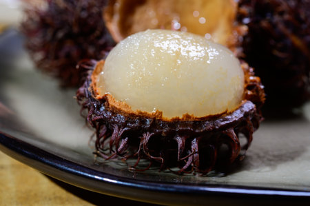 Tasty tropical exotic fruits, sweet ripe fresh peeled and unpeeled hairy rambutan southeast Asian...