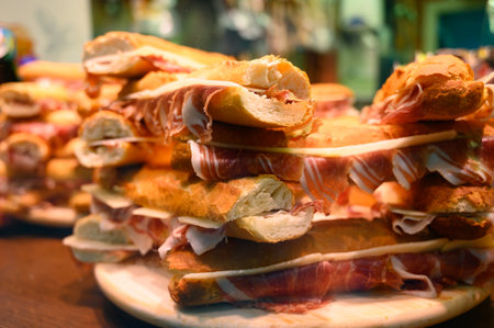 Spanish street food, fresh baked baguette bread with sliced iberian cured ham jamon, bocadillo close upの写真素材