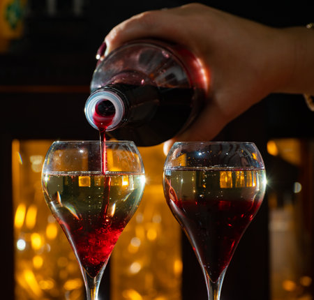 Drinking of Kir Royal, French aperitif cocktail made from creme de cassis topped with champagne, typically served in tulip glasses served in barの写真素材