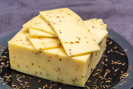 Cheese of Netherlands, piece of cow milk Dutch gouda cheese with dried aromatic cumin seeds close upの写真素材