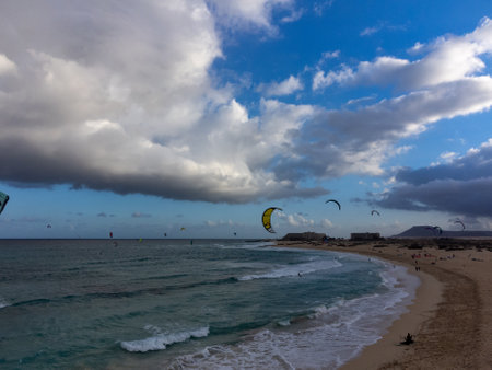 Aerial sunset view on white sandy Corallejo dunes, beach, ocean water waves and kite surfers at winter, Fuerteventura, Canary islands, Spainの写真素材