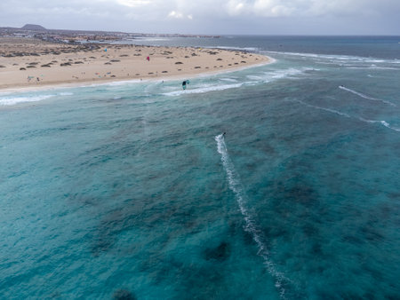Aerial sunset view on white sandy Corallejo dunes, beach, ocean water waves and kite surfers at winter, Fuerteventura, Canary islands, Spainの写真素材