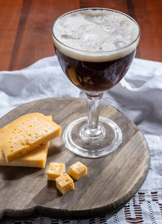 Glass of Belgian abbey brown beer and wooden board with old belgian cheese made by monks from cow milk, tastes of Belgiumの写真素材