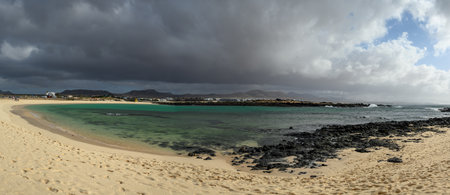 White sand, blue water and stormy clouds on La Concha beach, El Cotillo surfer's village,...