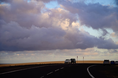 Driving car on black asphalt road through white sandy dunes near Corallejo beach at colorful sunset Fuerteventura, Canary islands, Spainの写真素材