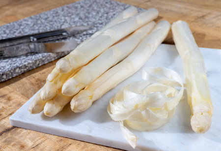 How to peel asparagus, spring season, new harvest of Dutch, German white asparagus, bunch of raw white asparagus on table close upの写真素材