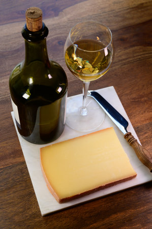 Wine and cheese pairing, local Comte cheese produced in the Franche-Comte region and glass and clavelin bottle special and characteristic yellow wine vin jaune from Jura region, Franceの写真素材