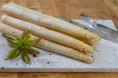 Spring season, new harvest of Dutch, German white asparagus, bunch of raw white asparagus on tableの写真素材