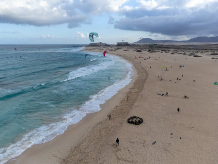 Aerial sunset view on white sandy Corallejo dunes, beach, ocean water waves and kite surfers at winter, Fuerteventura, Canary islands, Spainの写真素材